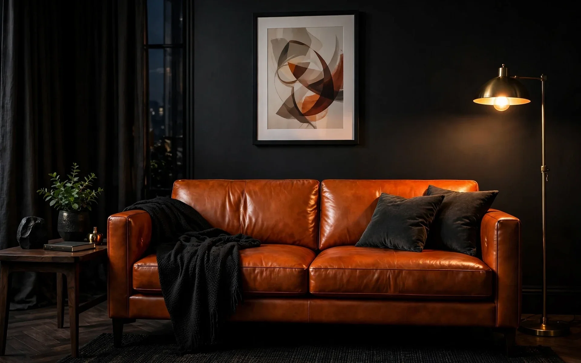 Cognac leather sofa ideas: caramel leather sofa glowing against dark charcoal walls with brass lighting